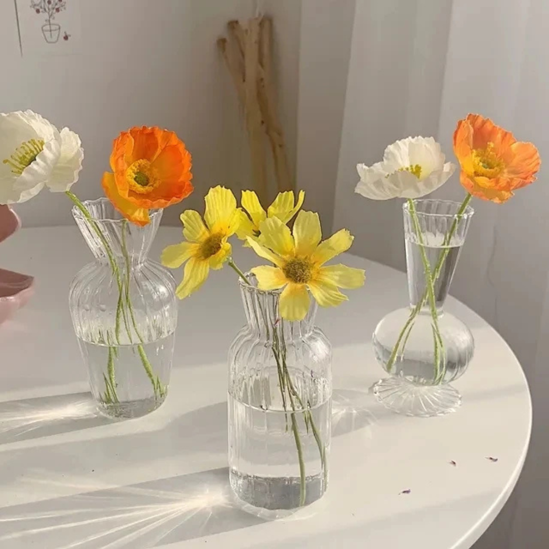 Conjunto de Vasos de Vidro para flores sob mesa com flor amarela dentro sob a mesa