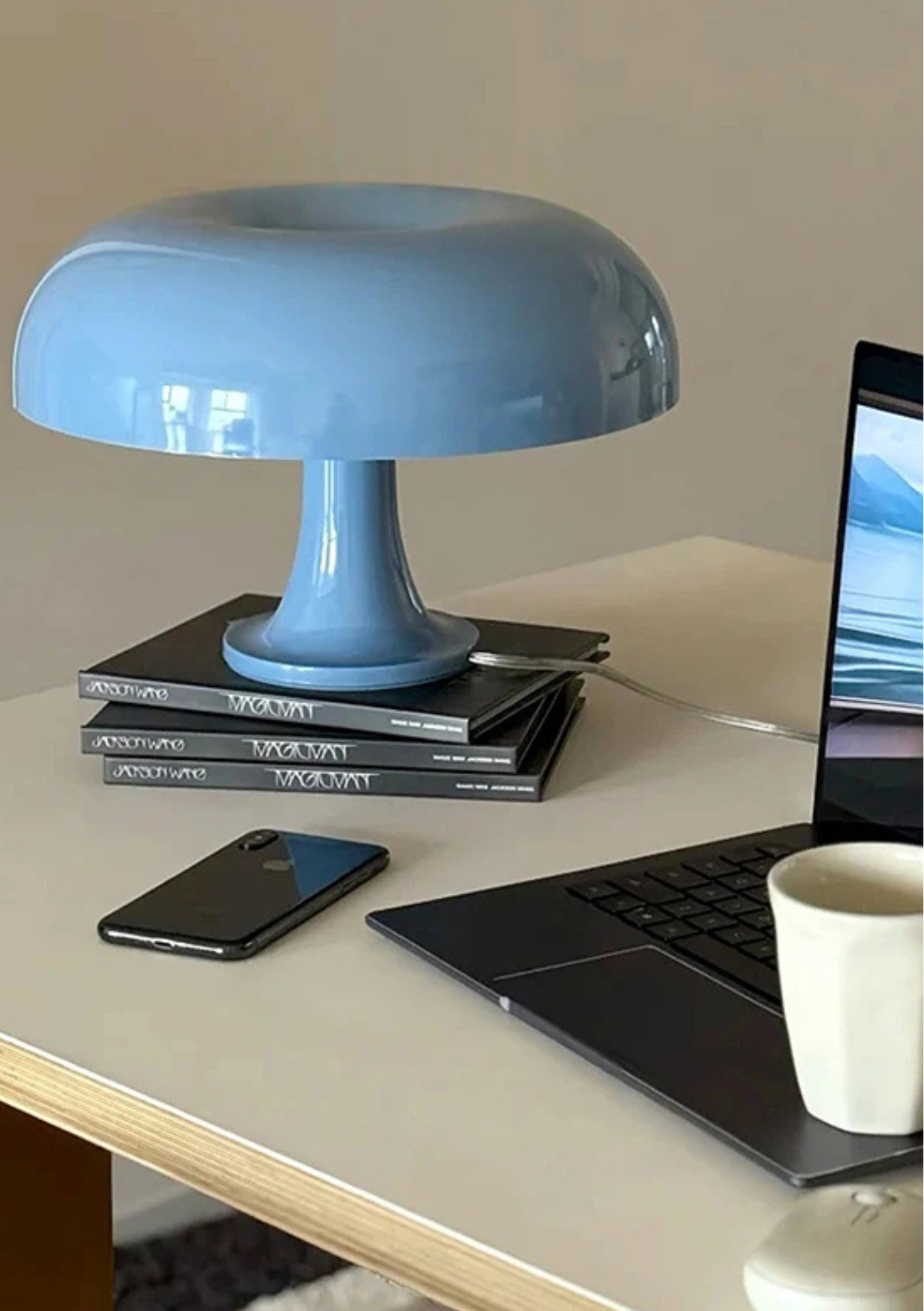 Candeeiro de Mesa azul sobre livros com celular e computador por perto