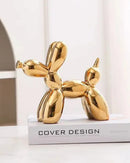 Escultura Decorativa de Cachorro dourado sob livro