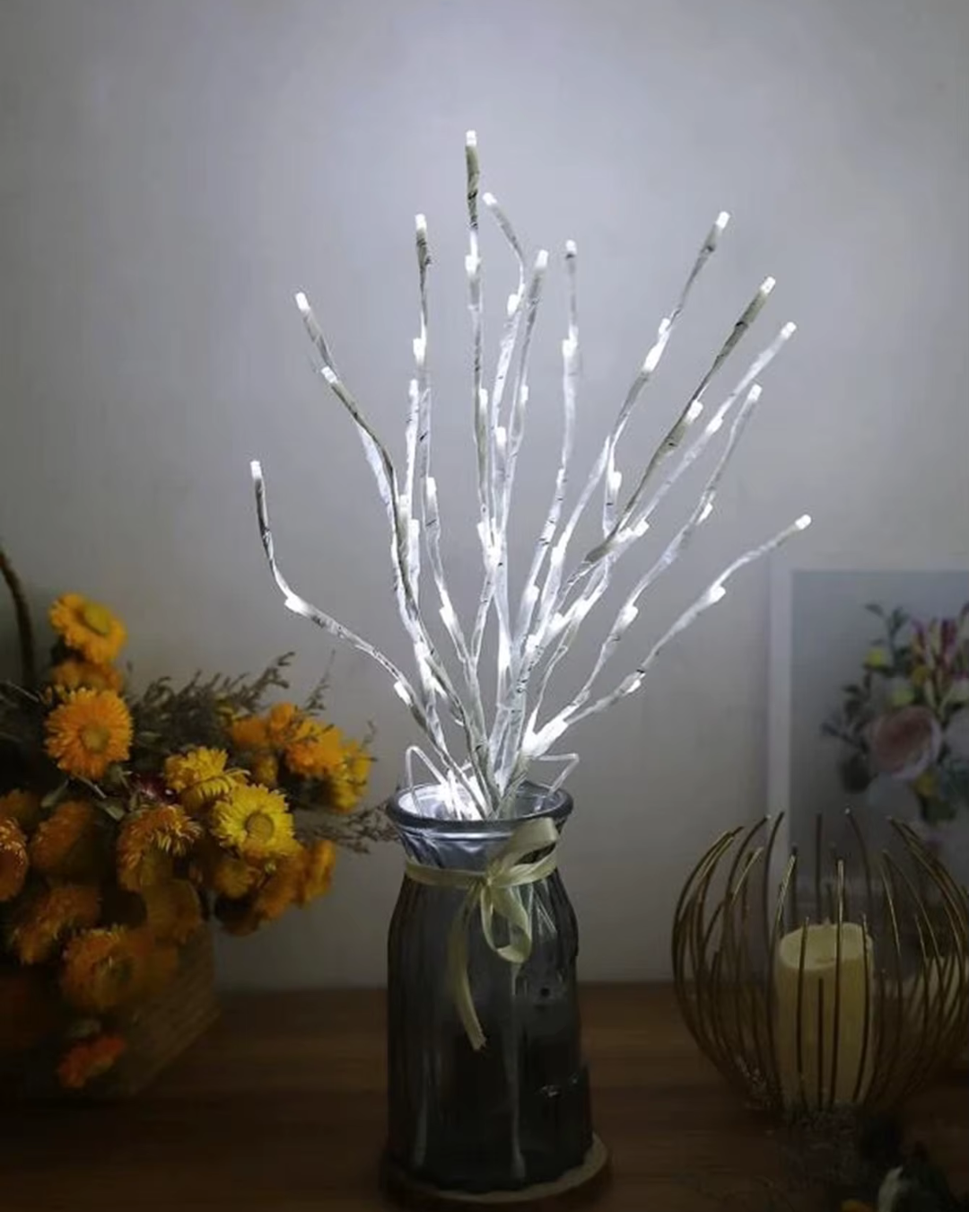 Galho Decorativo com Luzes LED Natal e Casamentos ao lado de flores e vela