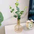 Vaso decorativo de ferro com flores dentro apoiado sob mesa perto de relógio