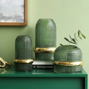 Conjunto de Vasos em Vidro Verde Escuro com planta dentro em cima de livro