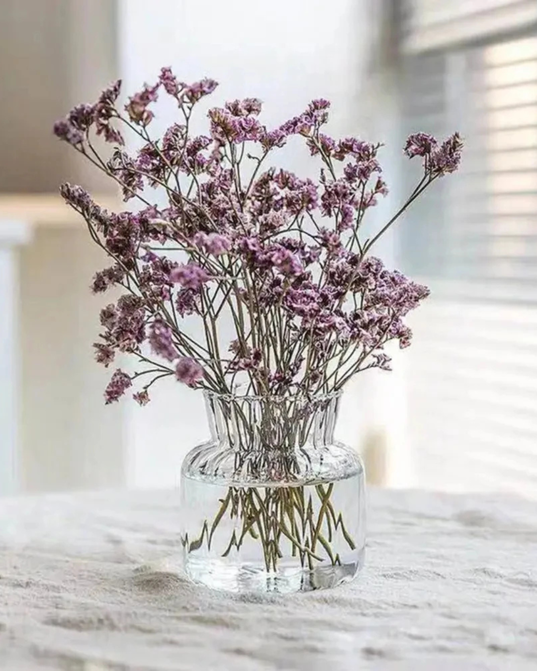 Vasos de Vidro para flores sob mesa com flor amarela roxa dentro