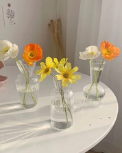 Conjunto de Vasos de Vidro para flores sob mesa com flor amarela dentro sob a mesa
