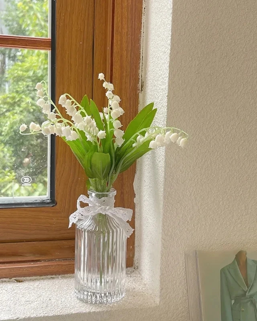 Vaso de Vidro para flores sob mesa com flores brancas dentro perto da janela