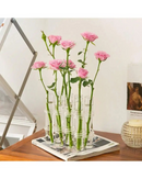 Vasos de vidro para decoração com flores apoiada sobre livros